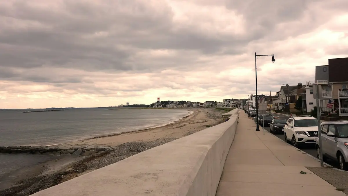 A seawall promenade along the beach with parked cars and houses alongside - Leak Detection in Beachmont